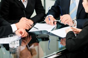 business leaders sitting at a desk discussing compliance