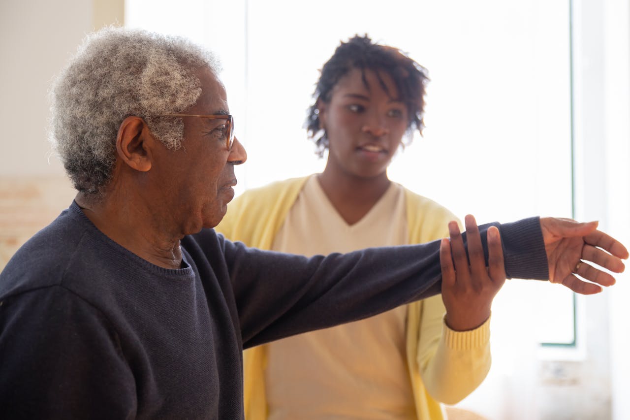 Woman Helping an Elderly Man in Doing Exercise